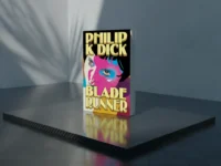 Livro Blade Runner com capa pop-art colorida em plataforma reflexiva sob sombras sutis em cenário minimalista.