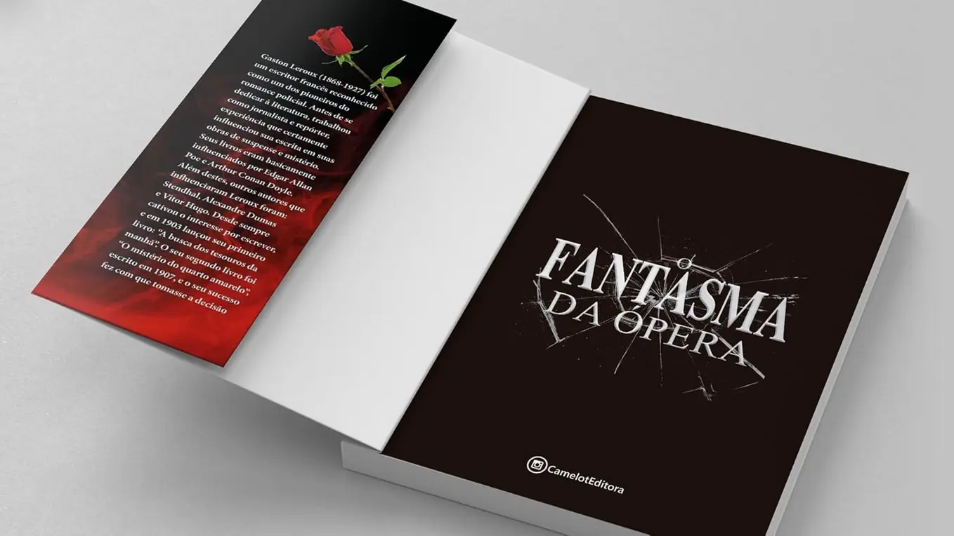 Livro O Fantasma da Ópera aberto em uma mesa com xícara de café