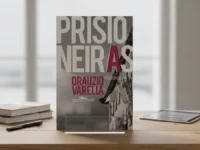 Capa do livro "Prisioneiras" em suporte sobre mesa.
