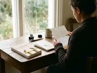 Ilustração de pessoa sentada à janela lendo uma carta, com envelopes sobre a mesa